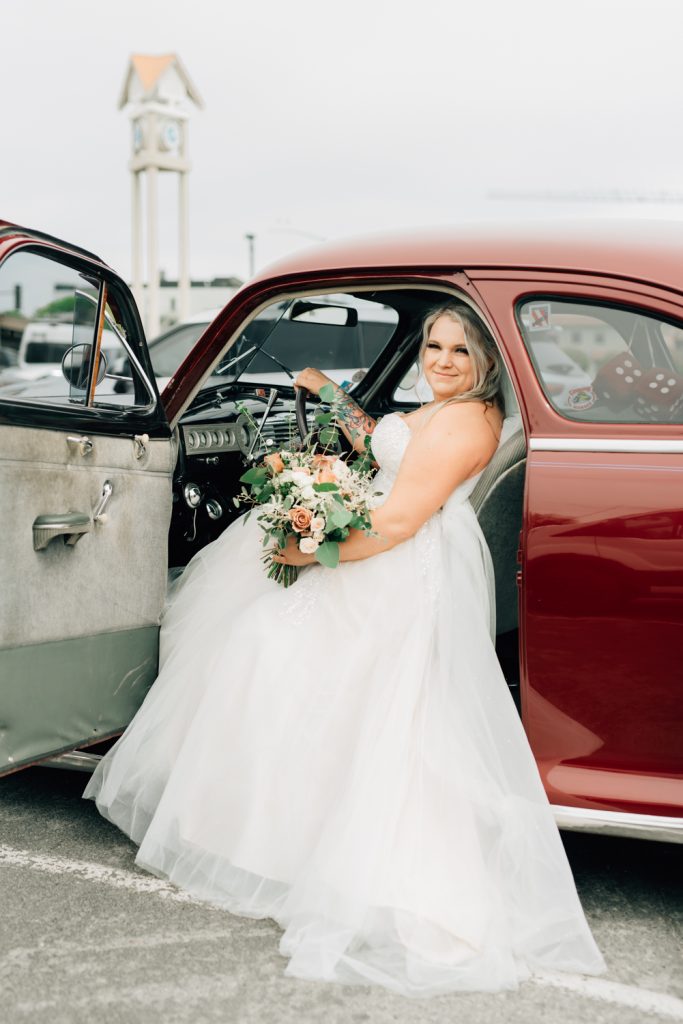 _A1S8935 Bride in wedding dress in red vintage car in downtown Coeur d'Alene id.